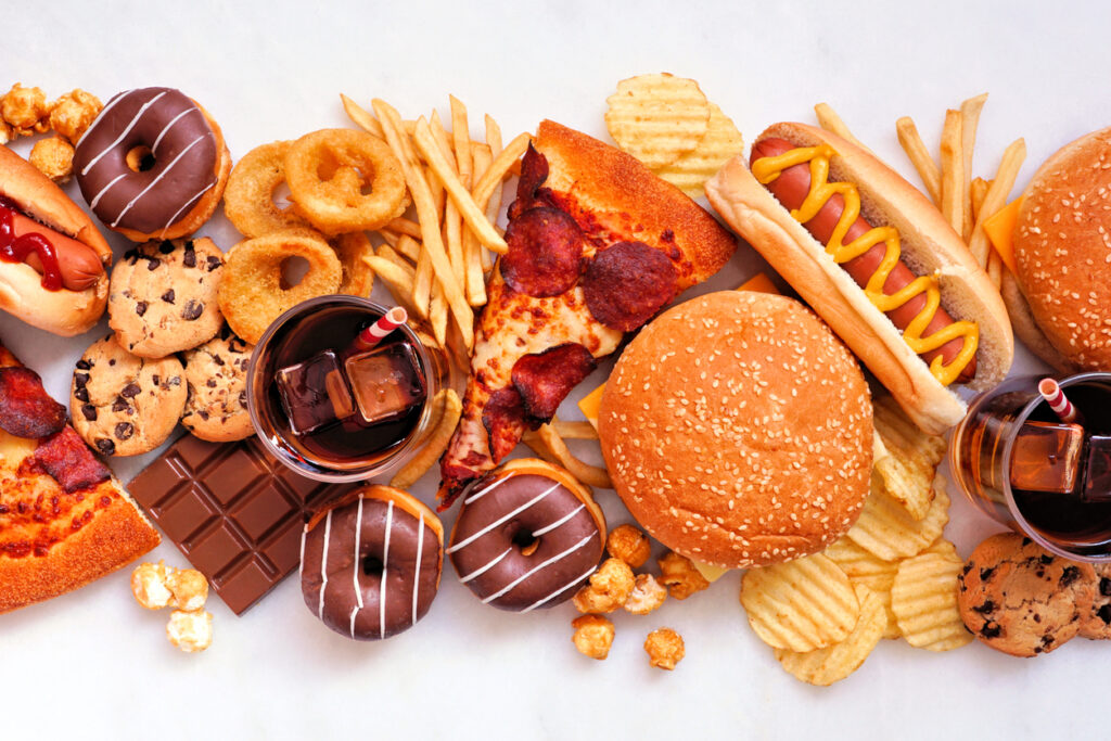 Collection of junk foods scattered over a white marble background