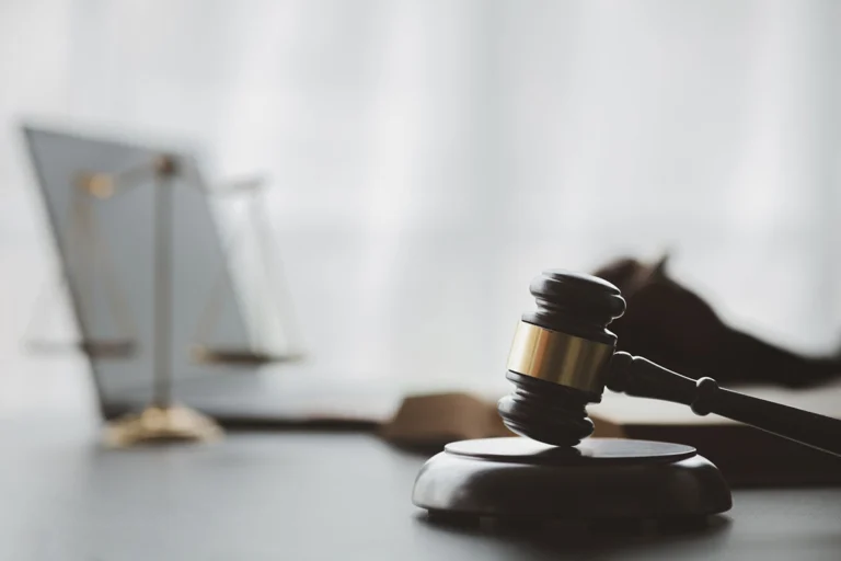 Image of a computer, gavel, and scales of justice sitting on a table.
