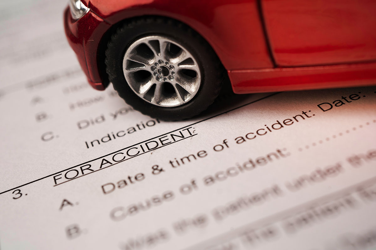A scale model of a car sits on top of a desk, with legal forms beneath it.