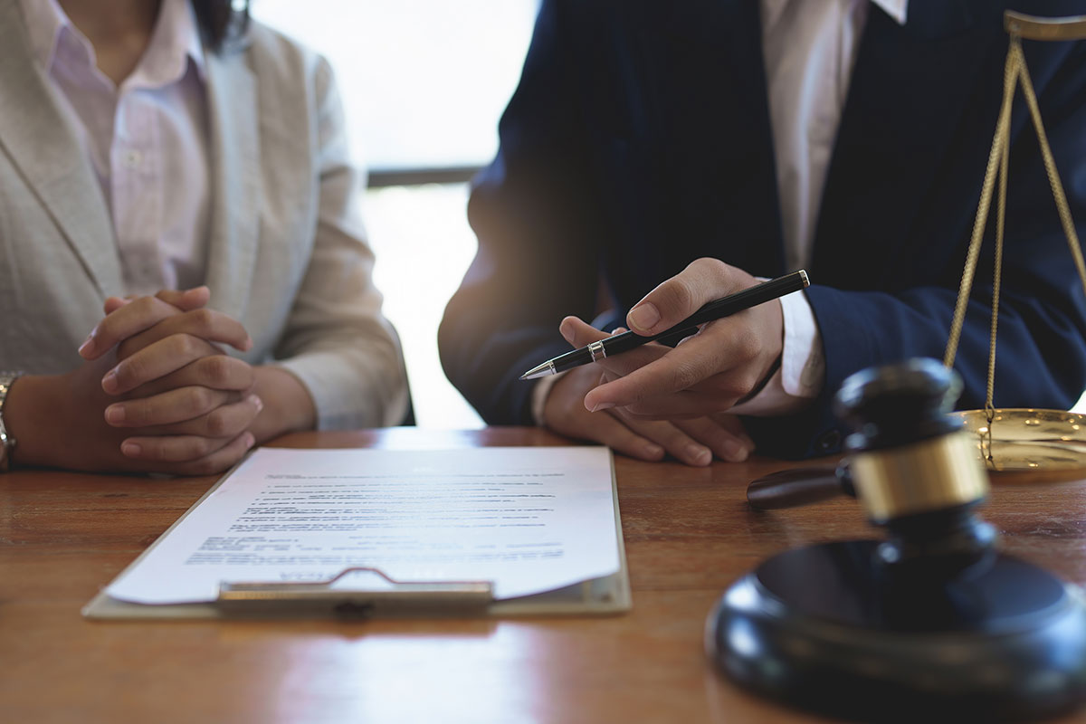 A client and her lawyer sit at a table reviewing documents.