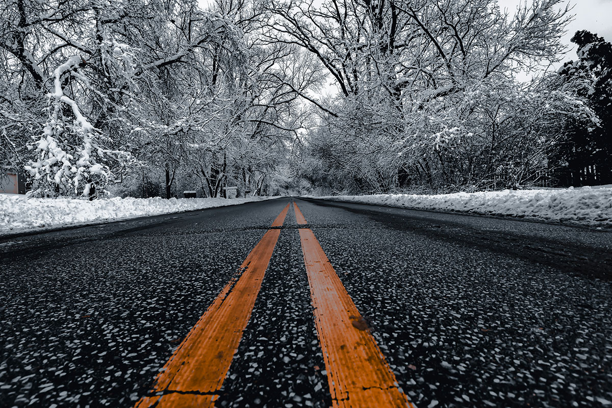A snowy road captured in black and white, illustrating the dangers of black ice and winter driving in Ohio.