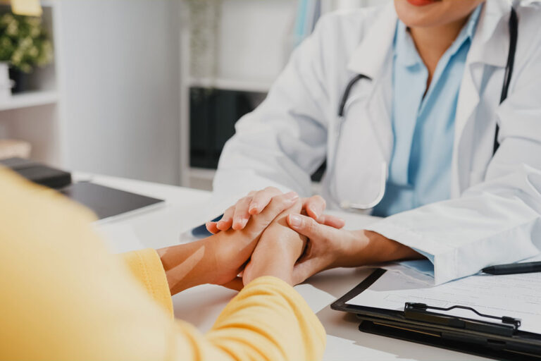 A doctor comforts a patient by holding their hands while discussing a brain tumor diagnosis associated with Depo Provera.