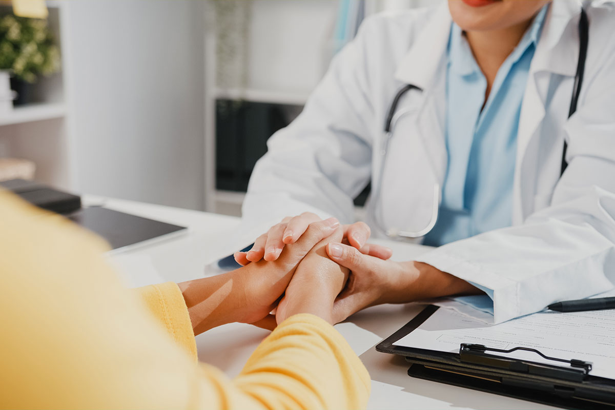 A doctor comforts a patient by holding their hands while discussing a brain tumor diagnosis associated with Depo Provera.