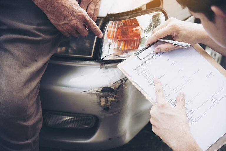A man examines a car while taking notes on a clipboard, considering how a minor accident may affect his Ohio insurance rates.