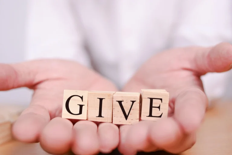 A set of wooden blocks arranged to spell "give," representing Slater & Zurz's commitment to community service in Ohio.