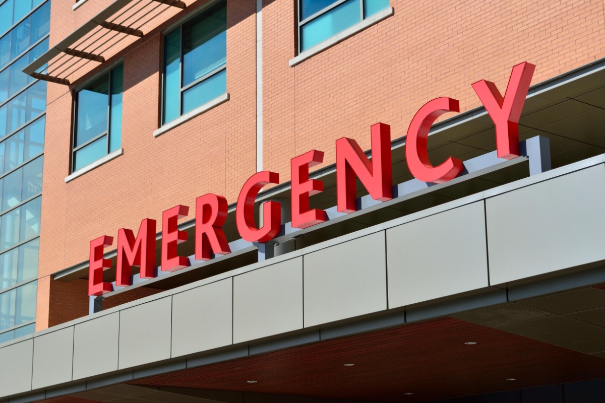 Bright red emergency sign on a building's exterior, signaling the presence of urgent medical services in the area.