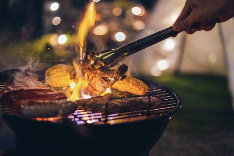 A person grilling food outdoors, highlighting the importance of safety to prevent grill-related accidents and fires.