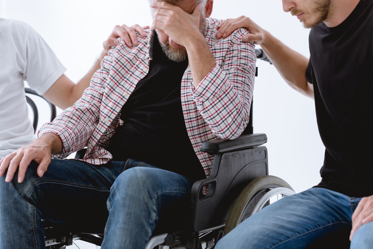 An Ohio man in a wheelchair sits beside two men, symbolizing support and resilience after trauma and injury recovery.
