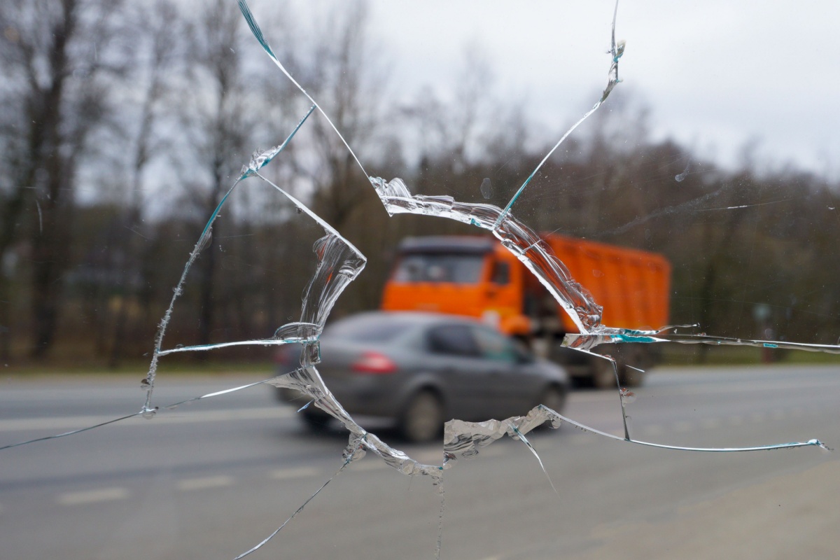 A broken windshield with a truck driving past, highlighting the aftermath of a truck accident involving unsecured cargo in Ohio.