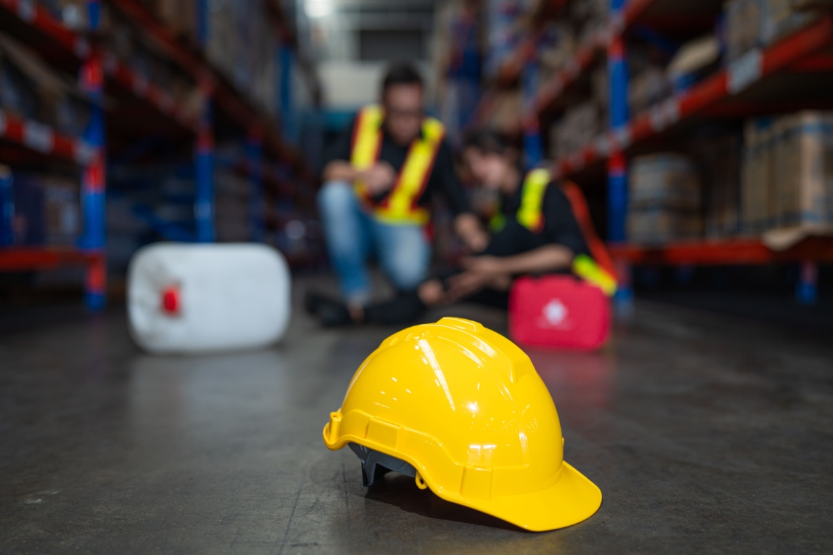 A worker and a hard hat sit on the warehouse floor, representing the challenges faced by injured warehouse employees in Ohio.
