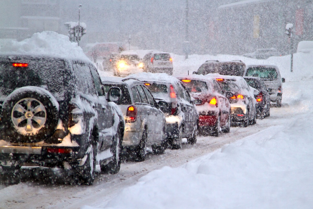 Snow-covered cars are driving slowly down an Ohio highway.