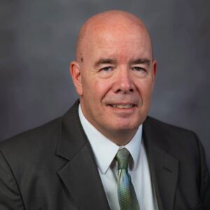 Jeff Hawkins sits in a suit and tie, representing Slater & Zurz, stands confidently for a professional portrait.