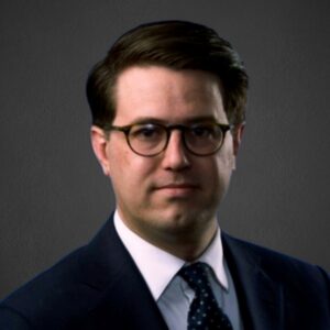 Parker Fox in a suit and tie, representing Slater & Zurz, stands confidently for a professional portrait.