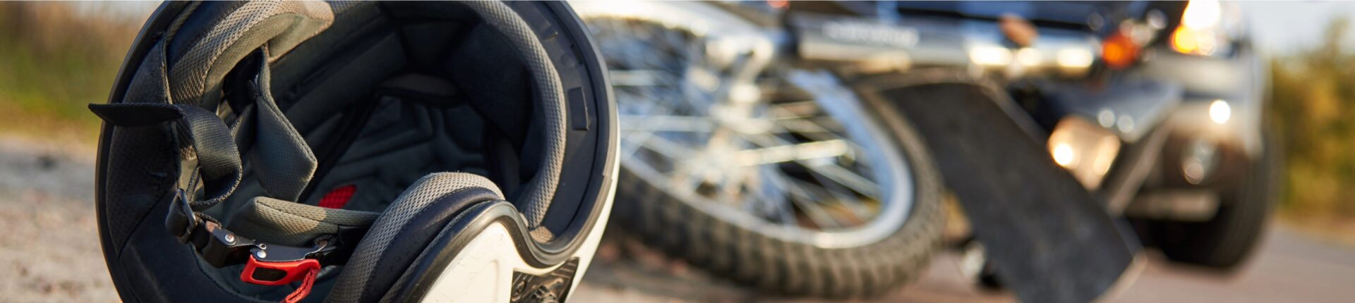 A motorcycle helmet is positioned on the ground next to a car, indicating a potential motorcycle accident scene.