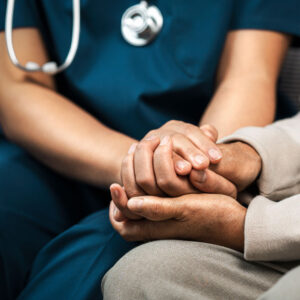 A nurse gently holds the hands of an elderly man, symbolizing care and compassion in a nursing home setting.