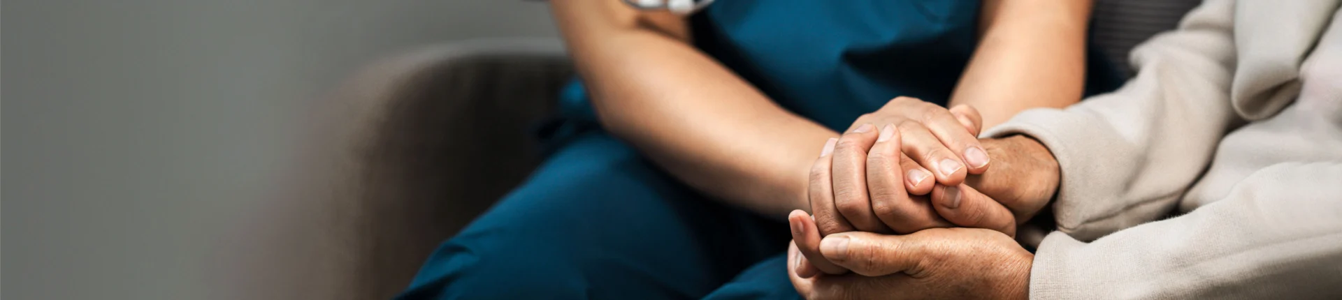 A nurse gently holds the hands of an elderly man, symbolizing care and compassion in a nursing home setting.