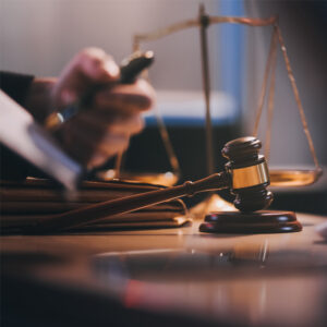 A lawyer points to a legal document with a pen. a gavel sits on the table in the foreground