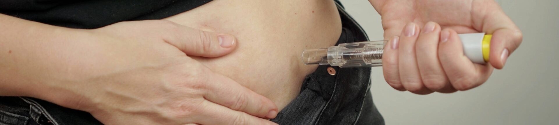 Woman using a GLP-1 injector to her stomach