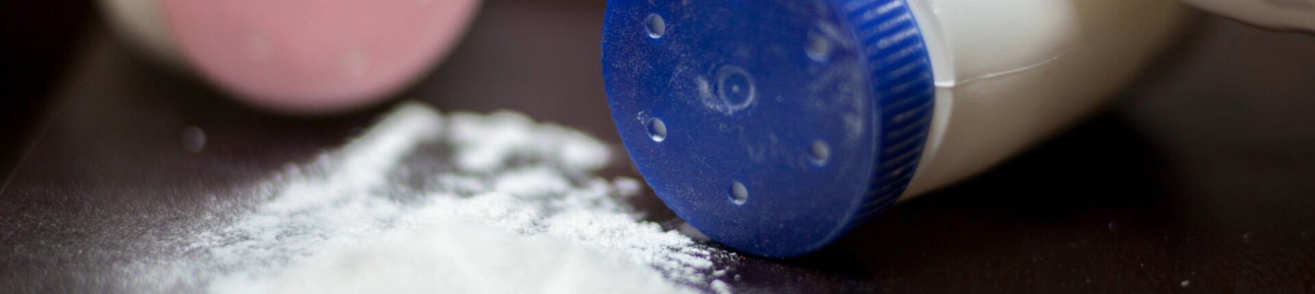 Talcum powder spilled on table with two containers in the background