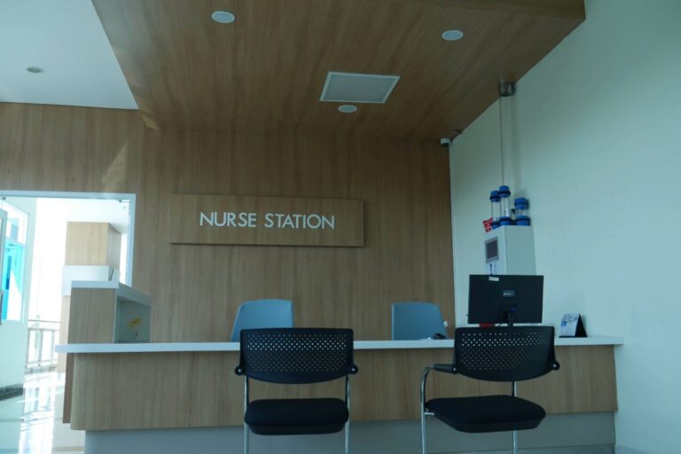A reception desk with two empty chairs in front, situated in an unoccupied nurses station at a nursing home.