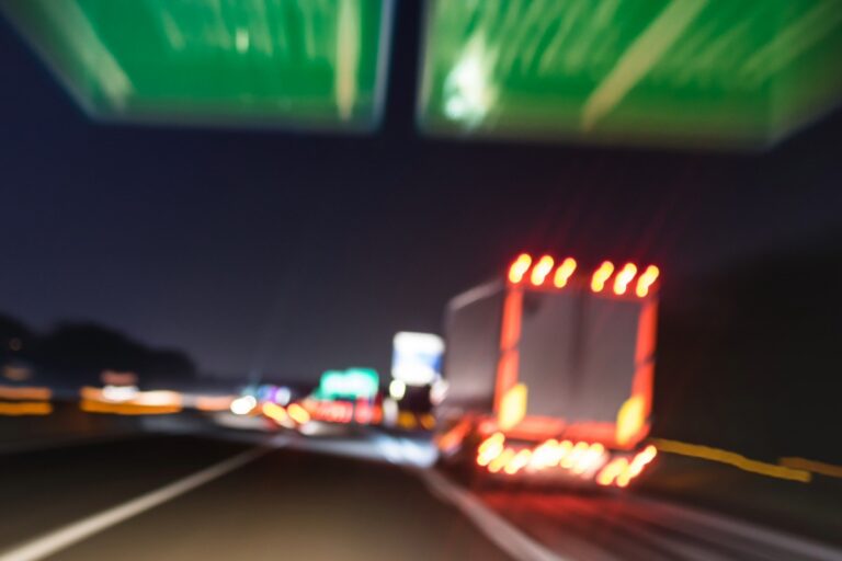 A blurry photo of a truck merging onto an Ohio highway at night, with illuminated road signs overhead and light trails visible.
