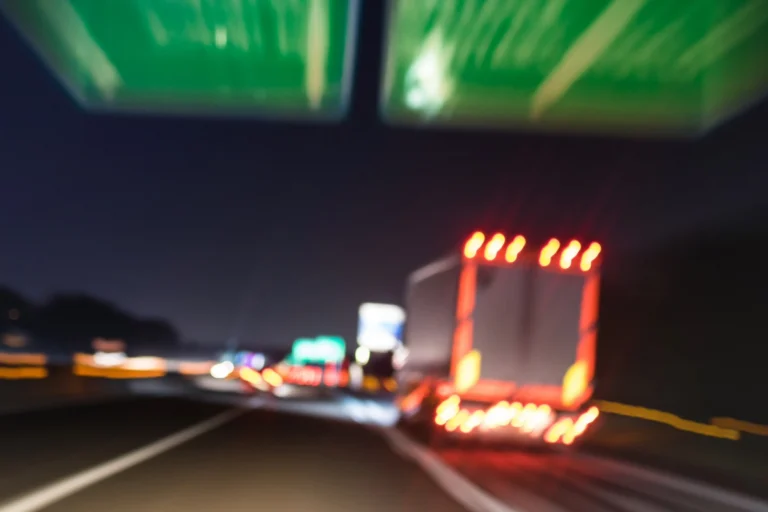 A blurry photo of a truck merging onto an Ohio highway at night, with illuminated road signs overhead and light trails visible.