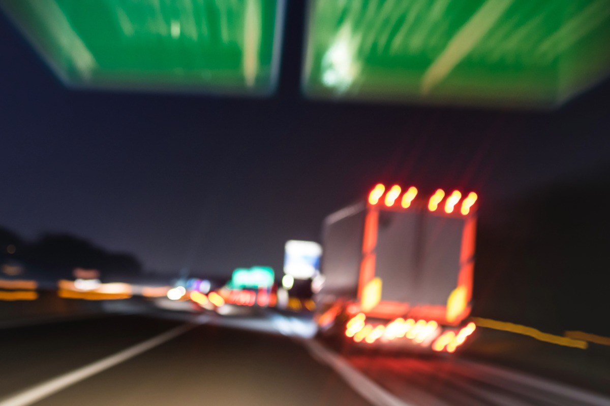 A blurry photo of a truck merging onto an Ohio highway at night, with illuminated road signs overhead and light trails visible.