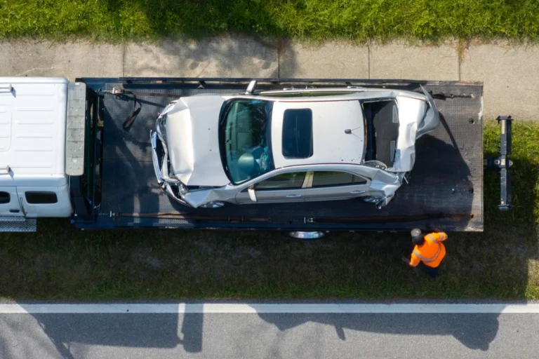 Aerial view of severely damaged silver sedan loaded onto tow truck after rear-end truck accident in Ohio – highlights catastrophic damage and urgency to preserve evidence