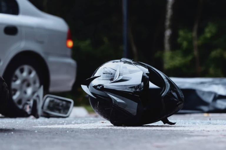 Black motorcycle helmet lying on the road after a left turn car accident in Ohio, with damaged car visible in background
