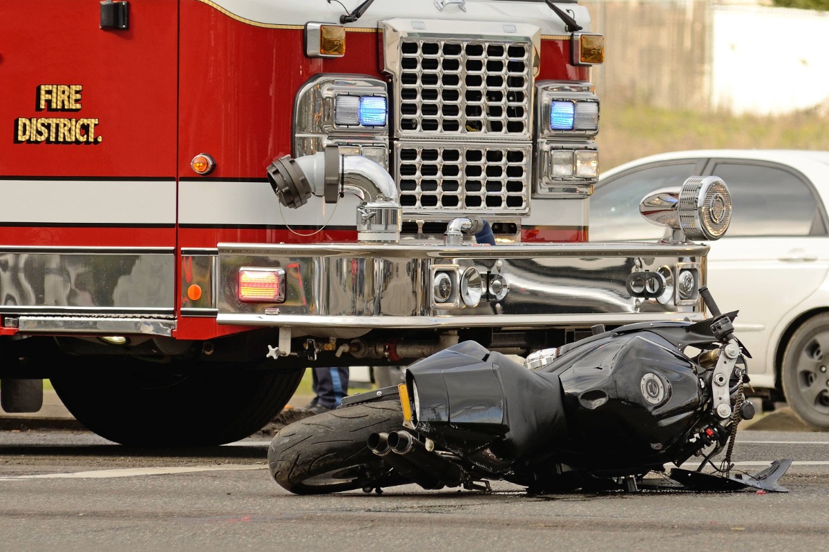 Serious motorcycle crash scene in Ohio showing overturned black motorcycle next to fire truck, illustrating the severe injuries that can result from motorcycle accidents.