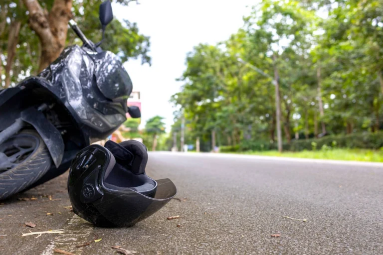 Overturned black motorcycle and helmet on Ohio road after crash – illustrating impact of Ohio motorcycle helmet law on injury claims