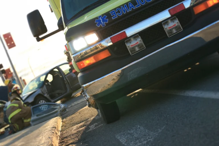 Ambulance at an intersection crash scene while firefighters tend to damaged cars after an Ohio impaired driving crash
